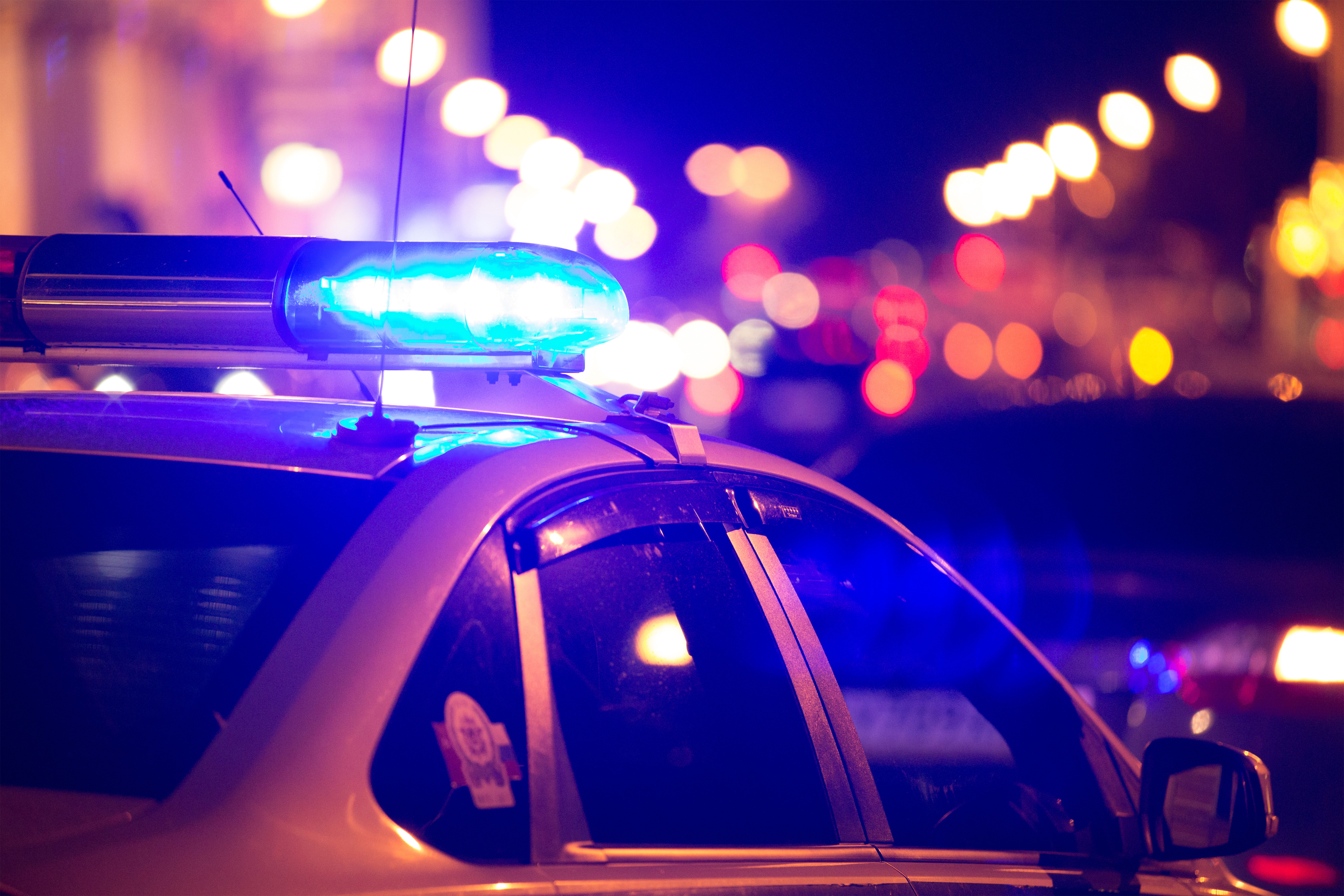 Blue light flasher atop of a police car. City lights on the background ...